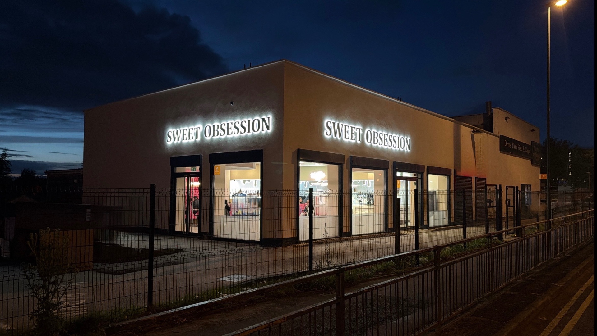 The Sweet Obsession parlour lit up at night on Manchester Street, Oldham